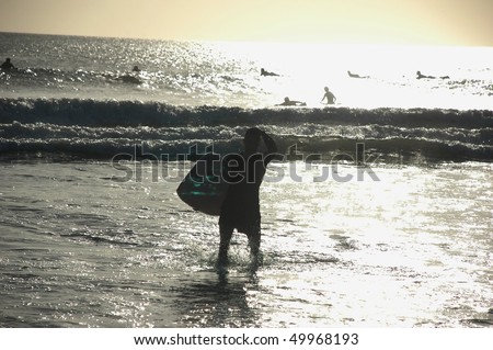 Male surfer coming back from the sea, Kuta, Bali, Indonesia.