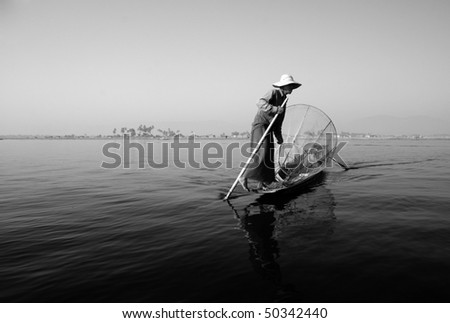 INLE LAKE, MYANMAR - FEB 12: fisherman rows his boat with his leg to catch fish on february 12, 2009 in Inle Lake, Myanmar.