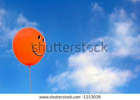 Red happy face balloon with blue sky at the background