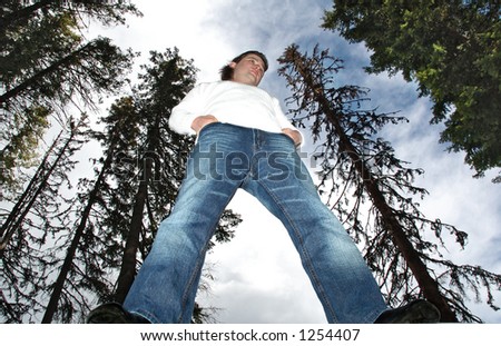 Man standing in middle of forest.Looking tall, photographed from below