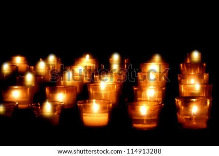 Soft golden glow of votive candles on church alter.