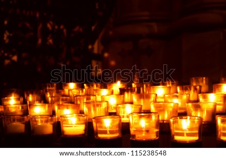 Many glowing votive prayer candles in church