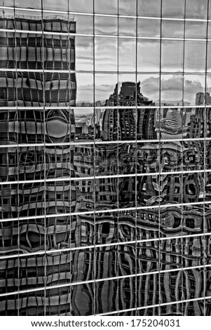 An abstract view of city buildings reflected in glass in grungy black and white.