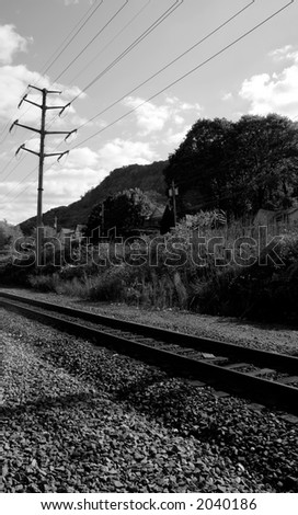 Train tracks pass through rural community; black and white