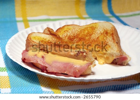 Grilled cheese and ham sandwich on paper plate