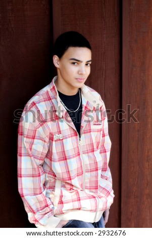 Multi-cultural teen boy wearing casual clothing standing against dark textured background