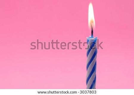 One blue and white lit birthday candle on pink background