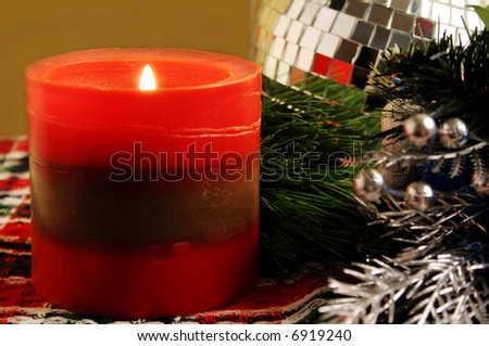 Lit red christmas candle with shiny silver ornaments
