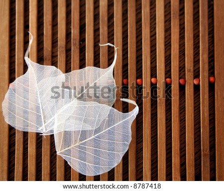 Scented transparent leaves on wooden slatted mat with orange beads