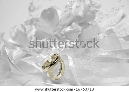 Wedding bands on ribbon with flowers and beads; selective coloring on rings