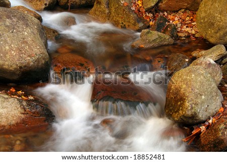 Soft swirling water over rocks in autumn