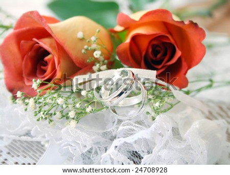 stock photo Red and orange rose on lace with wedding bands