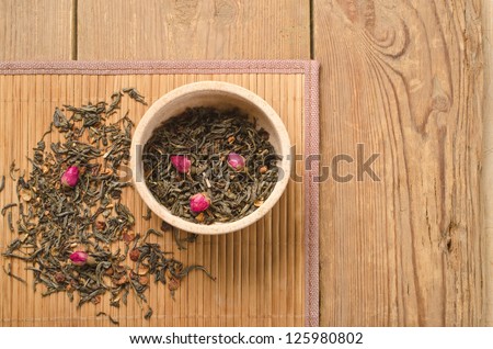Green tea with dried rose and fruit of rose hips on a wooden background