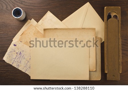 Old letters, paper, pencil box and inkpot on wooden background