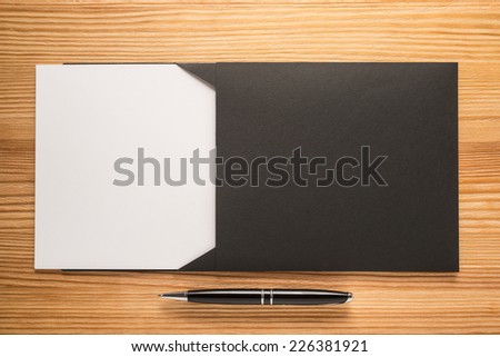 Black envelope with white paper and pen on the table