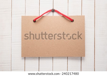 Paper signboard with rope on wooden background