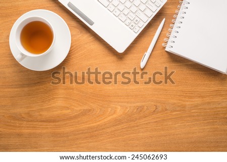 Office table with notepad, computer, pen and tea cup