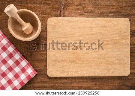 Cutting board with towel and bowl on wooden background