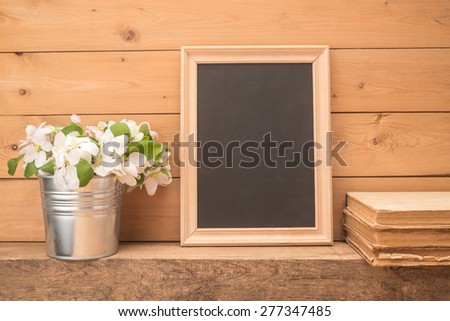 Wooden frame, flowers and old books on wooden background