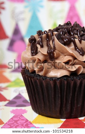 Chocolate, chocolate, chocolate cupcake on patterned party hat background.