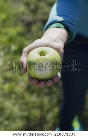 Girl holding a green apple she took a bite from.