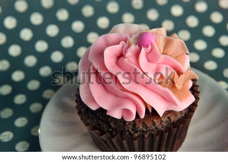 Cute cupcake on a decorative plate with a teal polka dot background