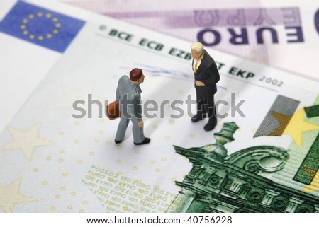 two businessmen figurines standing on euro banknotes, financial deal concept