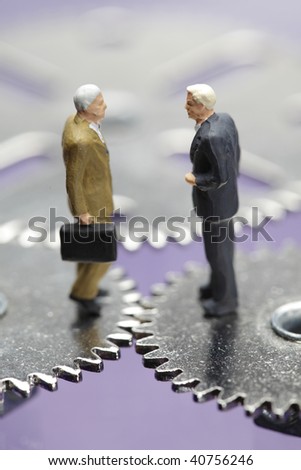 two businessmen figurines standing on cogwheels, financial deal concept