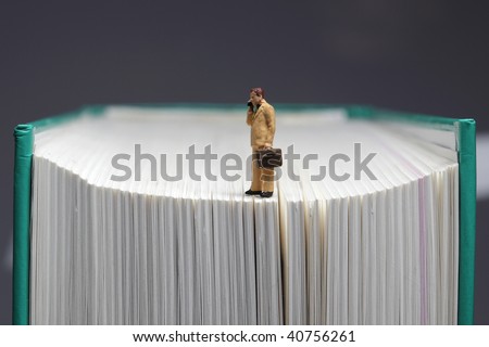 Figurine of businessman with handy standing on book, closeup