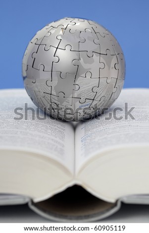 Metal puzzle globe on open book