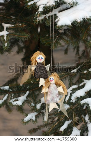 couple of victorian handmade toy angels on fir tree with snow vertical
