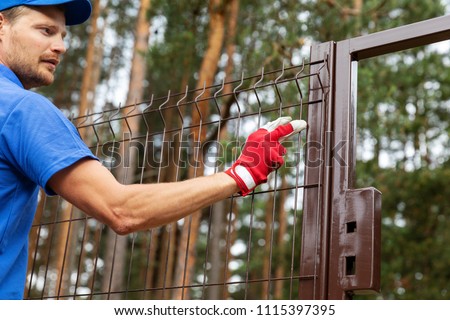 territory enclosure - worker installing metal fence