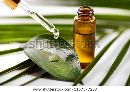 essential oil dripping on the green leaf from pipette