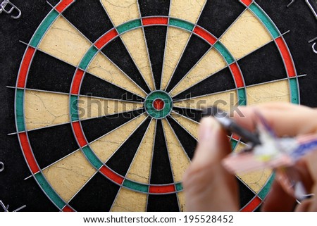 hand throwing dart to dartboard