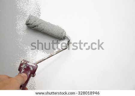 gray color painting wall with roller in hand