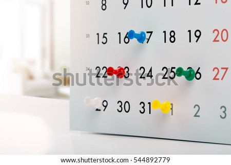 thumbtacks in calendar - concept of busy schedule