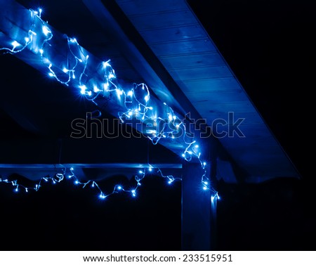 Fragment of a wooden terrace decorated with LED garland which shines blue light. Shallow DOF