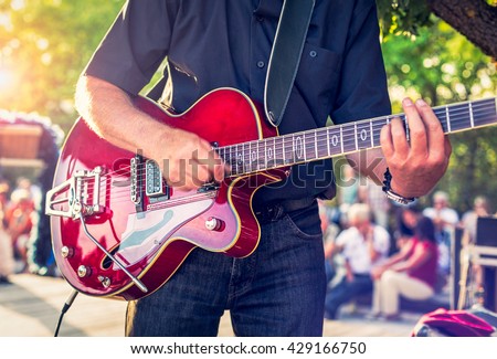 Man with a red electric guitar in the park playing a concert