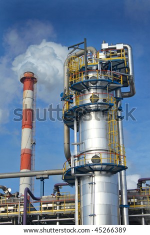 Heavy industry installation with white smoke over blue sky