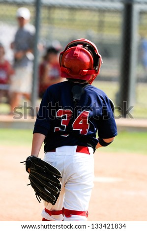 Youth baseball catcher walking about to home plate during a game.