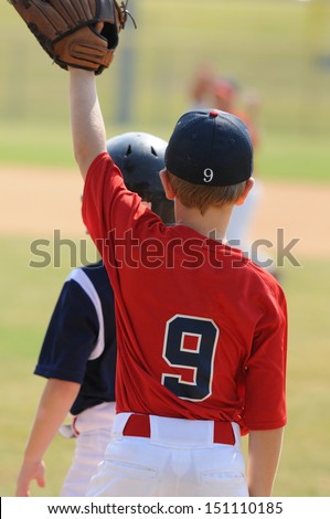 Little league baseball boy playing first base.