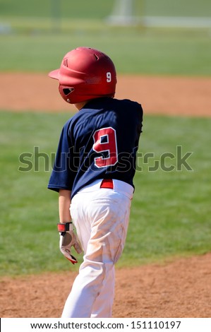 Little league baseball boy standing on base with helmet