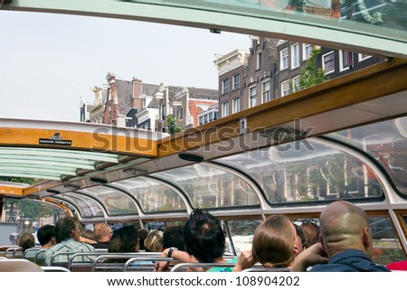 AMSTERDAM, NETHERLANDS - JULY 27 : Tourists watching Amsterdam from a canal boat on July 27, 2012. Amsterdam is the worlds most watery city. It has more than one hundred kilometres of canals.