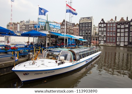 AMSTERDAM, NETHERLANDS - JUL 27: Tourist Canal boat cruises boat in Amsterdam on July 27, 2012.  Amsterdam has 1,200 bridges and 165 canals. Best way to experience them is one of the boat tours.