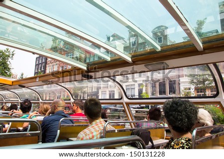AMSTERDAM, NETHERLANDS - JULY 27 : Tourists watching Amsterdam from a canal boat on July 27, 2012. Amsterdam is the worlds most watery city. It has more than one hundred kilometres of canals.