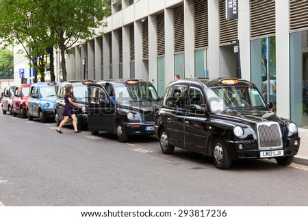 LONDON - JUL 2, 2015: Row of London Taxis lined up along the sidewalk. The London\'s iconic black cabs are a symbol of the city and a major attraction in themselves.