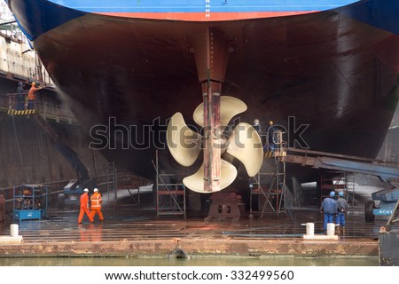 ROTTERDAM, NETHERLANDS - SEP 5, 2015: Workers removing algue in ship repair dry dock.