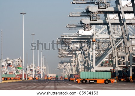 Harbor cranes and robot trucks with containers in a large port.
