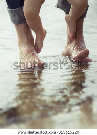 Bare feet father and his little son staying in the reflecting water