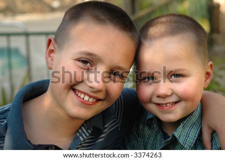 Big hug between two little brothers standing in their backyard